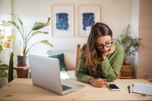 Gelangweilte Frau im Home Office vor ihrem Laptop